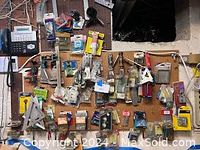 Wide view of assorted tools, hardware, telephone, and spackle on pegboard