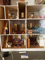 Interior view showing fully furnished rooms with wallpaper, furniture, dolls, stairs