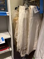 White vintage linen tablelinens with lace, embroidery, and cutwork hanging on hangers