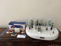 Full view of the winter wonderland skating pond scene including figurines and trees arranged on ceramic pond base