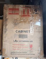 Original cardboard packaging box for the bedside table labeled 'CABINET' with fragile handling instructions and SKU visible.