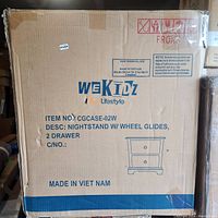 Box showing the brand WeKidz Lifestyle, item number CGCASE-02W, product description as nightstand with wheel glides and 2 drawers, made in Vietnam