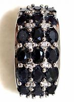 Close-up of sterling silver ring set with multiple oval dark blue sapphires and smaller clear stones arranged in rows on band