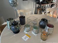 Lot of assorted candle holders on a table, showing variety of materials and styles