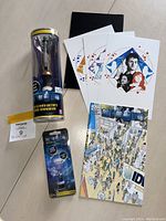 Photo showing all Doctor Who collectibles together: two sonic screwdriver replicas in packaging, three art cards, and Doctor Who comic book.