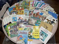 Wide view of approximately 40 vintage children's books spread out on a table showing various classic titles and colorful illustrated covers.
