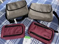 Two gray shoulder messenger bags and two maroon zippered Abbvie-branded cases laid on blue striped fabric, showing front and top views.