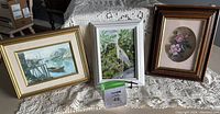 Image showing three framed artworks: coastal scene, crane painting by Peggy Holcroft, floral painting