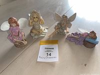 Four fairy and Thumbelina figurines displayed on a reflective floor, showing all items clearly.