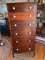 Front view of the full dresser showing six drawers with white porcelain pulls and keyholes, dark wood with brass inlay lines on drawers.