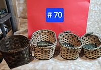 Four baskets against red backdrop: one dark brown square basket and three round nesting baskets with handles