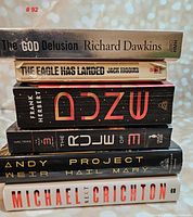 Stack of six books seen from above with titles visible on spines, placed sideways on a surface with a sparkly background.