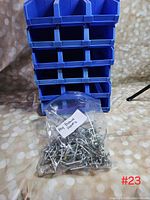 Blue plastic storage bins stacked with a bag of metal peg board hooks labeled 'Peg Board Hooks' placed in front.