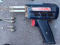 Close-up of Weller 8200 soldering gun showing brand label, dual tips, and two of the metal attachments.