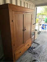 Front view of solid pine armoire showing two doors, lower drawer, wooden knobs