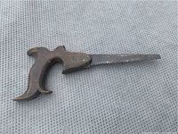 Image showing full view of antique poke saw with devil horns shaped wooden handle and short toothed metal blade