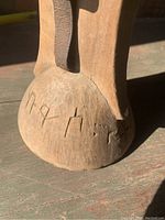 Close-up of the carved inscription on the rounded base of the wooden head rest pillow, showing Ethiopian script characters.