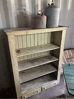 Front view of the antique dresser showing 4 shelves and 2 bottom drawers with worn light paint finish.