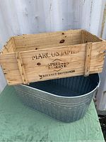 Wooden wine crate placed inside the metal beer tub, showing branding and fire stamp on the crate.