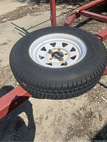 Spare tire with white steel rim mounted on trailer frame