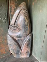 Front view of one carved stone figure with distinct modernist abstract facial features, polished multicolored stone.