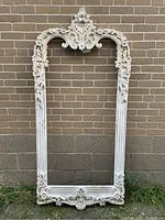 Full view of the large rectangular decorative wall frame against a brick background showing the overall structure and condition.