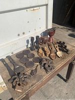 Full view of all carved wooden items arranged on rustic wooden table showing spoons, plates, bowls, and figures