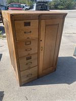 Full view of the oak antique file cabinet showing five drawers and a cupboard door.