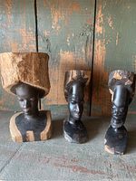 Photo showing the three carved busts displayed side by side, highlighting the different sizes and details in the wood carving and natural tree limb bases.