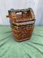 Front and side view of McCoy cookie jar shaped like a wishing well with clear ceramic glaze and raised detail