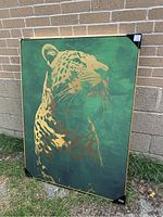 Frontal view of the golden leopard painting showing the green background and the gold-painted animal with minor scuffs on edges.