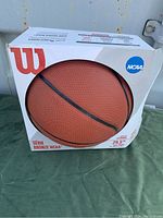 Front view of boxed Wilson NCAA Bronze Series basketball featuring visible ball and branding on package.