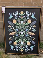 Front view of the framed floral print canvas with hummingbirds and butterflies on a black background.