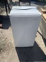 Front view of small white Danby refrigerator with power cord on top.