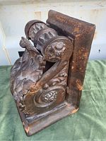 Angled side view showing the intricate acanthus leaf and floral scroll design on the cast steel doorstop with rust patina.