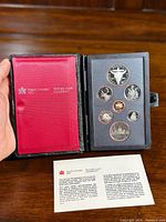 Proof set coins arranged in protective black foam inside black leather case, shown with closure latch and inner red lining with Royal Canadian Mint logo.