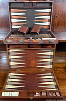 Photo of first backgammon set open, showing board design, checkers, dice and leather dice cups