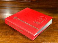 Closed red binder album with gold foil title “First Day Cover” on front