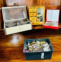 Overview of the estate jewelry lot including beige jewelry box, wooden jewelry box, red box, and black container filled with assorted jewelry.