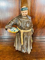 Front view of the Royal Doulton Jovial Monk figurine showing detailed facial features and objects held in hands.