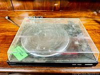 Front angle view of the Sony LX-150H turntable inside a clear plastic dust cover showing scuffs and scratches.