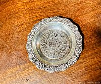 Top-down view of the small sterling silver dish showing the detailed embossed Mayan sun calendar design at the center and floral scalloped rim.