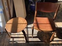 Photo showing both the wooden chair and round wooden table together with lighting casting shadows, highlighting their shapes and condition.