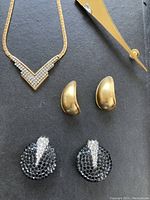 Full set including the necklace, two pairs of earrings (one gold-tone pierced, one black rhinestone clip), and a pin.