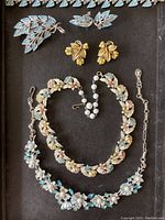 Photo showing all six Coro jewelry pieces together on black background including brooches, earrings, and two necklaces.