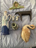 Top view of lot showing Wedgwood vase, Frankoma swan figurine, Crate and Barrel cruets, small green-grey vase, and smaller metal dog figurine.