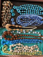 Overview photo of 9 plastic necklaces in various colors and bead styles, and 2 pairs of matching earrings.