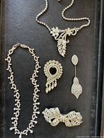 Full lot view showing 2 rhinestone necklaces and 3 rhinestone pins arranged flat on black background.