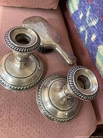 Pair of sterling silver Gorham candlesticks and a clothes brush shown on a fabric background