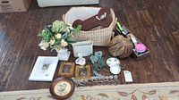 Overall lot showing basket, vase with faux flowers, framed art, coat hanger, curtain hangers, faux pumpkin, stapler, and other small decor items